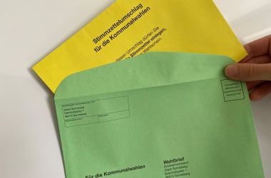 Ein gelber Umschlag steckt in einem grünen Umschlag.