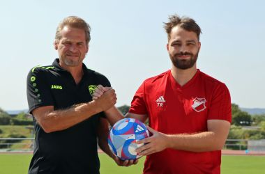 Zwei Männer halten einen Fußball.