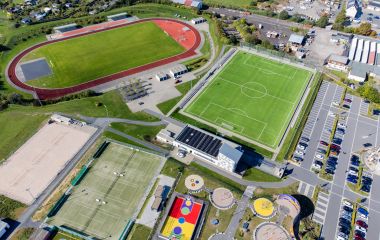 Ein Luftbild - zu sehen sind von oben ein Parkplatz, ein Fußballplatz, ein Leichtathletik-Sportfeld, Tennisplätze, eine Beachvolleyballanlage und ein Freizeitareal für Kinder und Jugendliche. Foto: J. Uebe