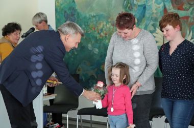 Der Bürgermeister Dr. Heiko Voigt überreicht eine Urkunde und Blumen an ein kleines Mädchen.