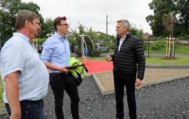 Drei Männer stehen auf einer Baustelle und sprechen miteinander.