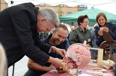 Auf einem Tisch stehen Biologiemodelle. Ein Mann steht davor und baut eines der Modelle zusammen. Es ist der Bürgermeister Dr. Heiko Voigt.
