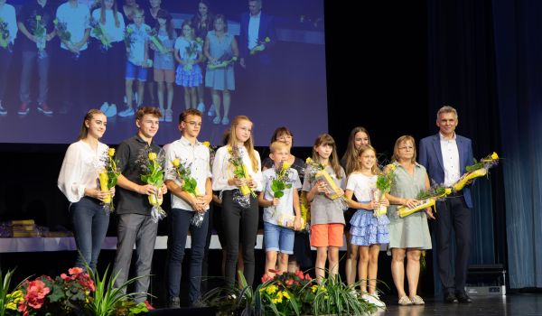 Kinder stehen mit Präsenten auf einer Bühne.