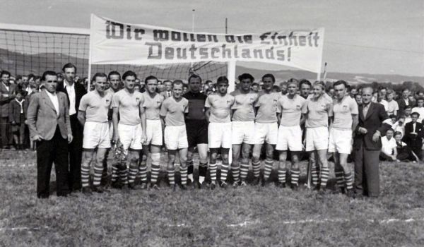 Eine Fußballmannschaft im Jahr 1949 mit dem Transparent "Wir wollen die Einheit Deutschlands".