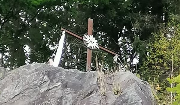 Ein Gipfelkreuz auf einem Stein.