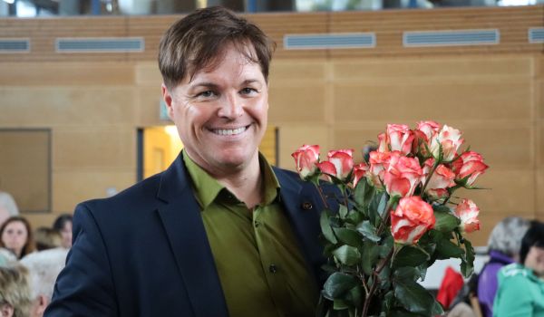 Ein Mann hält einen Strauß mit Rosen.