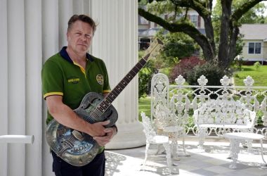 Ein Mann hält eine Gitarre aus Metall in der Hand.