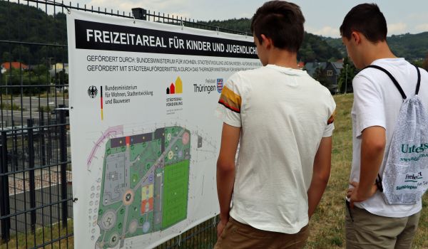 Jugendliche schauen sich einen Bauplan des Freizeitareals an.