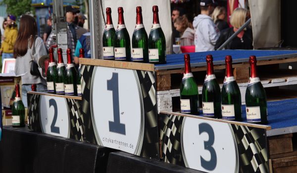 Sektflaschen stehen auf einem Siegerpodest.