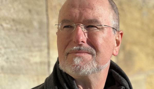 Ein Mann steht vor einer Sandsteinmauer.