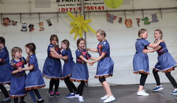Kinder tanzen pärchenweise auf einer Bühne.