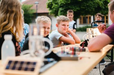 Kinder sitzen an einem Tisch mit Wasserstoff-Experimenten.