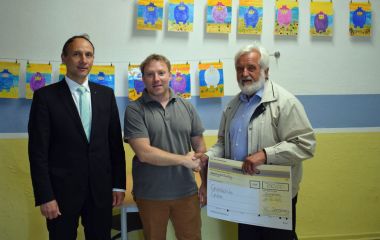 Zwei Männer überreichen einen Spendencheck an einen Lehrer. Es sind der Präsident von Rotary Sonneberg und der hauptamliche Beigeordnete der Stadt Sonneberg.