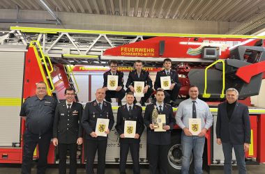 Feuerwehrkameraden stehen vor einem Drehleiterauto.