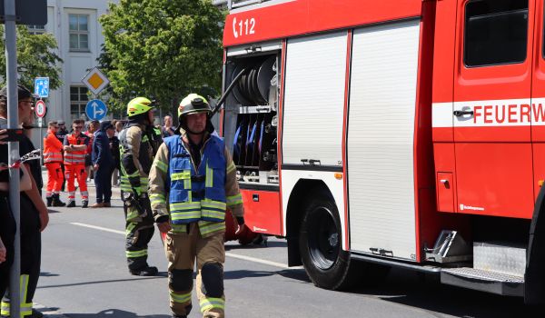 Männer in Feuerwehrkleidung neben einem Feuerwehrauto.