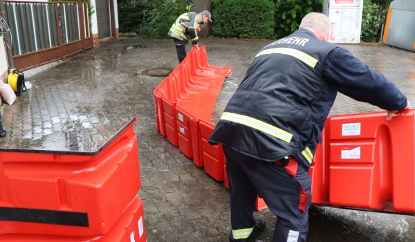 Zwei Feuerwehrmänner bauen einen mobilen Hochwasserschutz auseinander.
