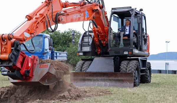 Der Bürgermeister Dr. Heiko Voigt sitzt in einem Bagger und gräbt symbolisch das erste Loch.