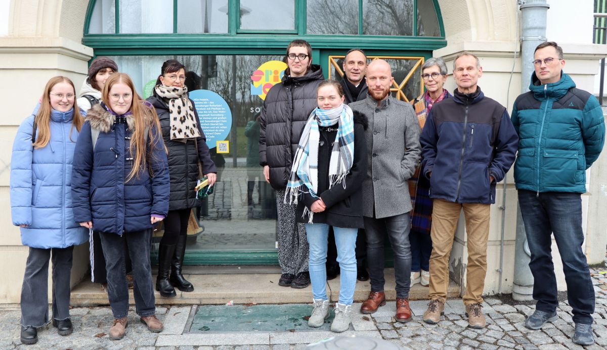 Eine Gruppe von Männern und Frauen steht an einem Schaufenster.