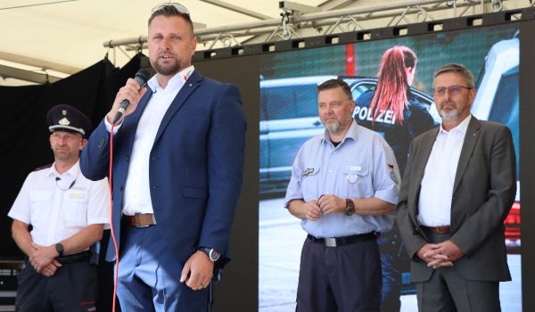 Ein Mann steht auf einer Bühne und hält ein Mikrofon in der Hand.