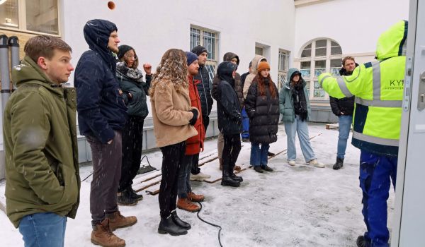 Menschen stehen nebeneinander vor einem Container. Es liegt Schnee.