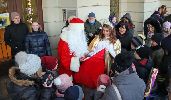 Der Weihnachtsmann und das Christkind umgeben von vielen Kindern.