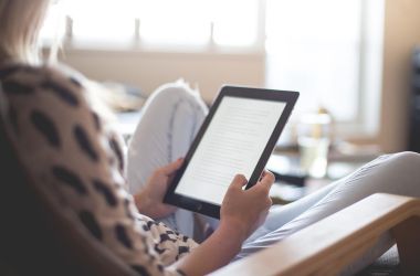 Junge Frau, sitzend von hinten, hält E-Reader in der Hand / Pixabay: Pexels
