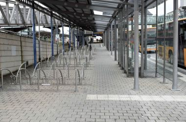 Fahrradständer unter einer Metallkonstruktion mit Dach und daneben Busspuren.