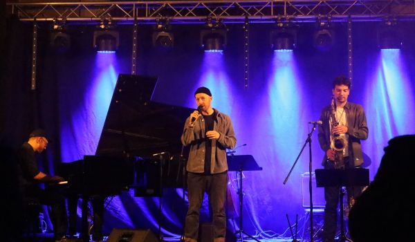 Drei Männer stehen auf einer Bühne und treten auf.