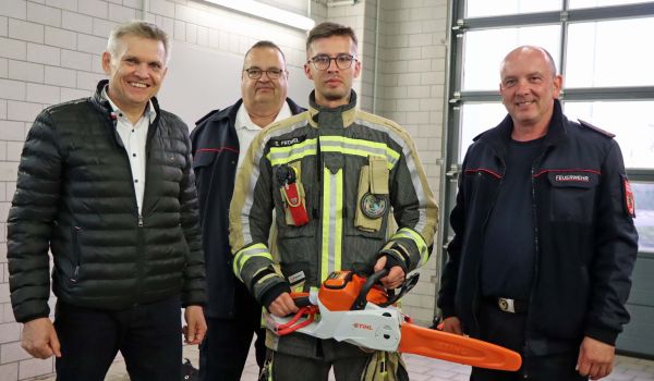 Vier Männer stehen in einer Garage und einer davon hat eine Motorsäge in der Hand.