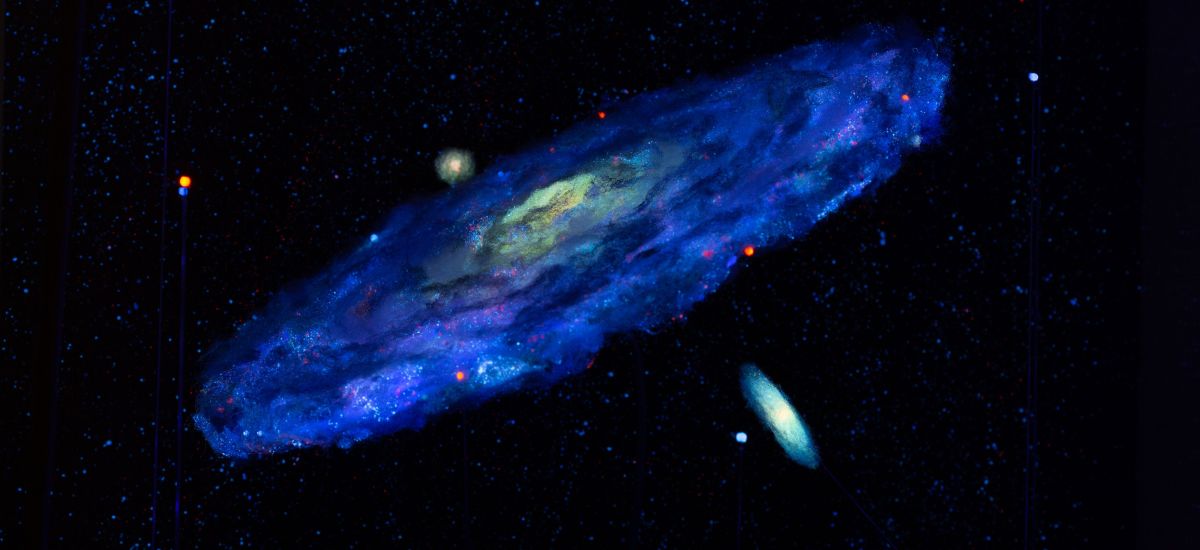 Ein Galaxiemodell leuchtet im dunkeln.