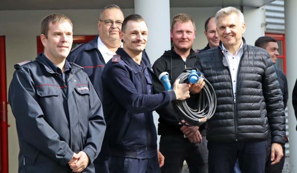 Eine Gruppe von Feuerwehr-Kameraden hält ein Kabel in der Hand.