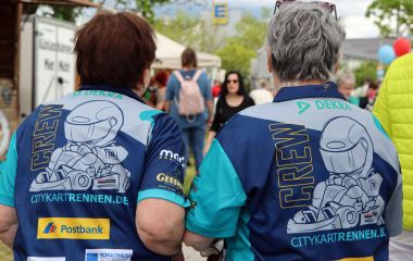 Zwei Helferinnen in blauen Werbetrikots von hinten.