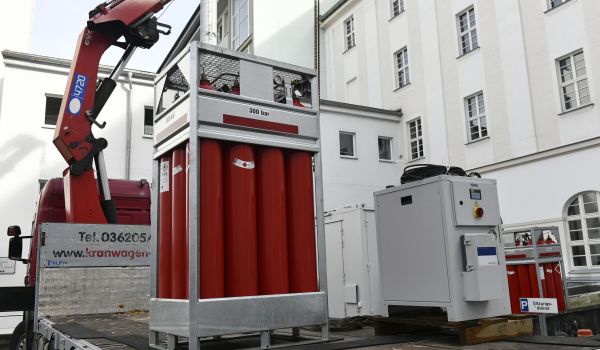 Ein Metallgestell mit roten Gasflaschen darin, steht auf einer LKW-Ladefläche.