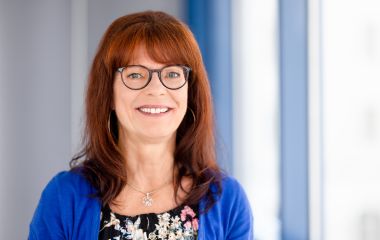 Eine Frau steht vor einem Fenster. Es ist Kerstin Bosecker aus dem Sekretariat der Kämmerei.