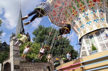 Ein Kettenflieger steht neben einer Kirche.