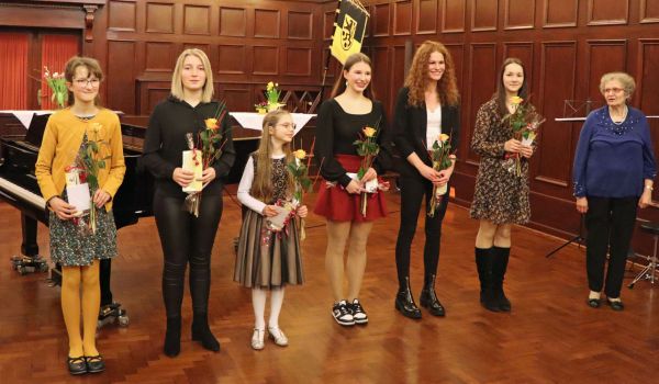 Kinder und Jugendliche stehen in einer Reihe und halten ein Präsent in den Händen.