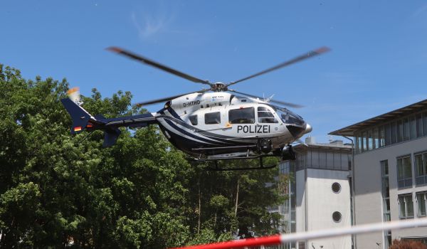 Ein Polizei-Hubschrauber landet auf einer Wiese.