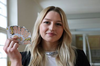 Eine junge Frau hält kleine Karten in der Hand.