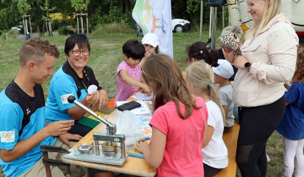 Kinder sitzen an einem Tisch und basteln.