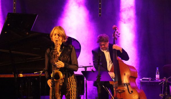 Ein Frau spielt Saxophon auf einer Bühne. Neben ihr spielt ein Mann Kontrabass.