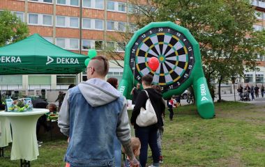 Menschen stehen vor einer riesigen aufblasbaren Dartscheibe.