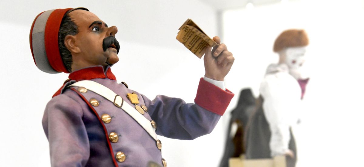 Ein Zirkusfigur hält einen Zettel in der Hand.