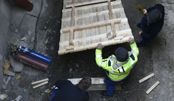Drei Männer bauen ein Holzfundament auf den Boden.