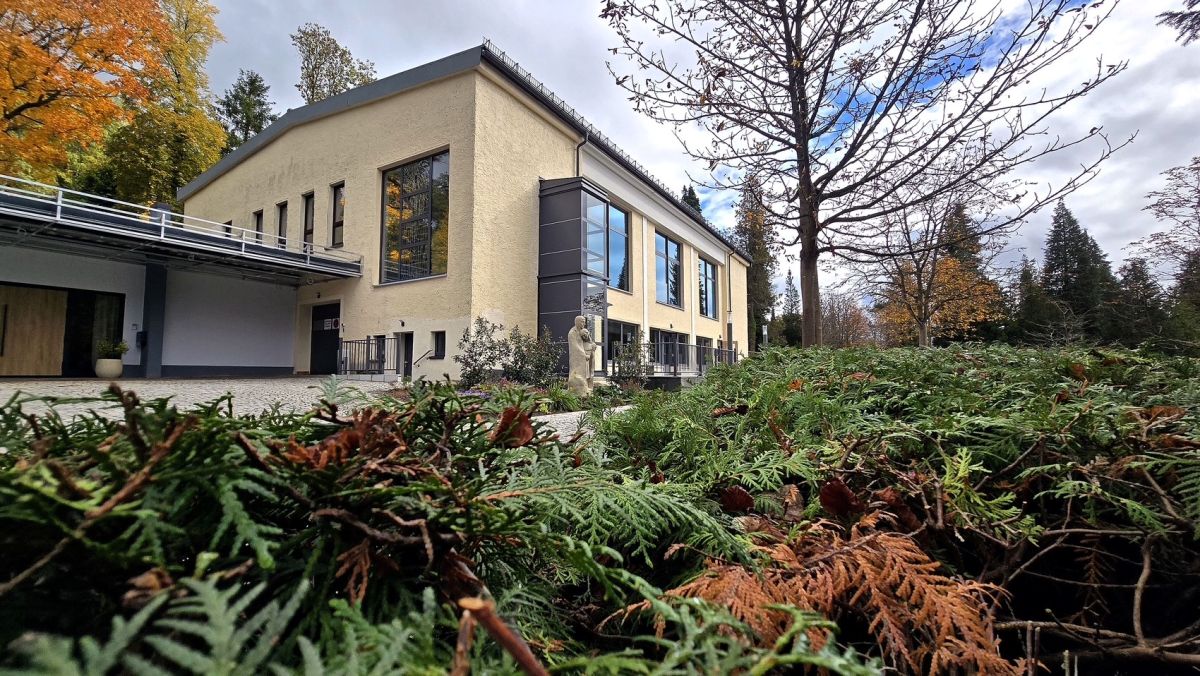 im Zentrum des Fotos steht ein gelbes Gebäude mit großen Fenstern. Es ist die Trauerhalle mit Krematorium auf dem Hauptfriedhof Sonneberg.