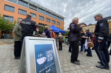 Polizisten und Passanten stehen ins Gespräch vertieft auf einem Marktplatz.