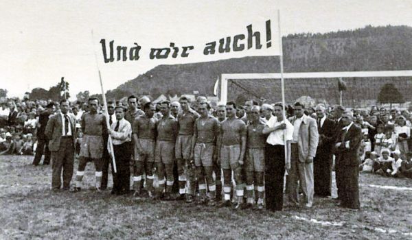 Eine Fußballmannschaft im Jahr 1949 mit dem Transparent "Wir auch".