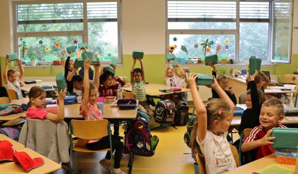 Kinder halten eine Brotdose in die Höhe.