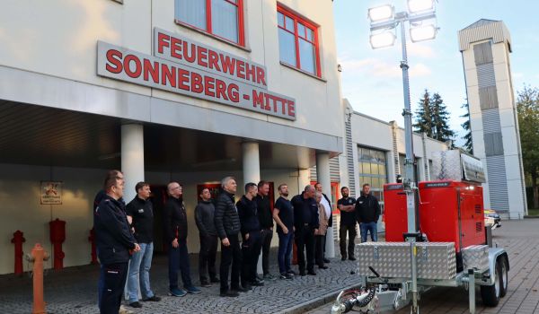 Eine Gruppe von Männern steht vor einem Feuerwehr-Gebäude.