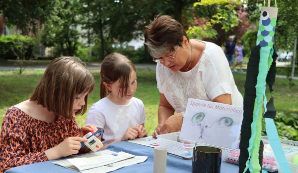Kinder sitzen an einem Tisch und basteln.