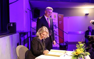 Eine Frau trägt sich in das Goldene Buch der Stadt Soonneberg ein.